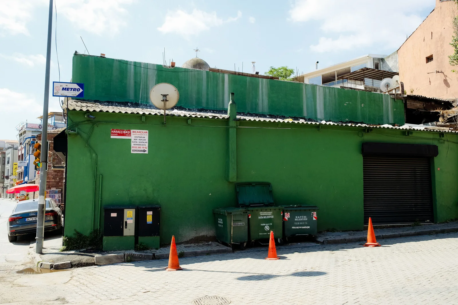 Street view of a vibrant green building with a dumpster on a sunny day. Atlanta Dumpster Rental Dispatch: Street Permit Workflow