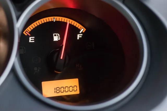 Close-up image of a car's fuel gauge showing a full tank with an odometer reading of 180000 miles. Dumpster Rental Job Costing: A Per-Load Tracking Sequence