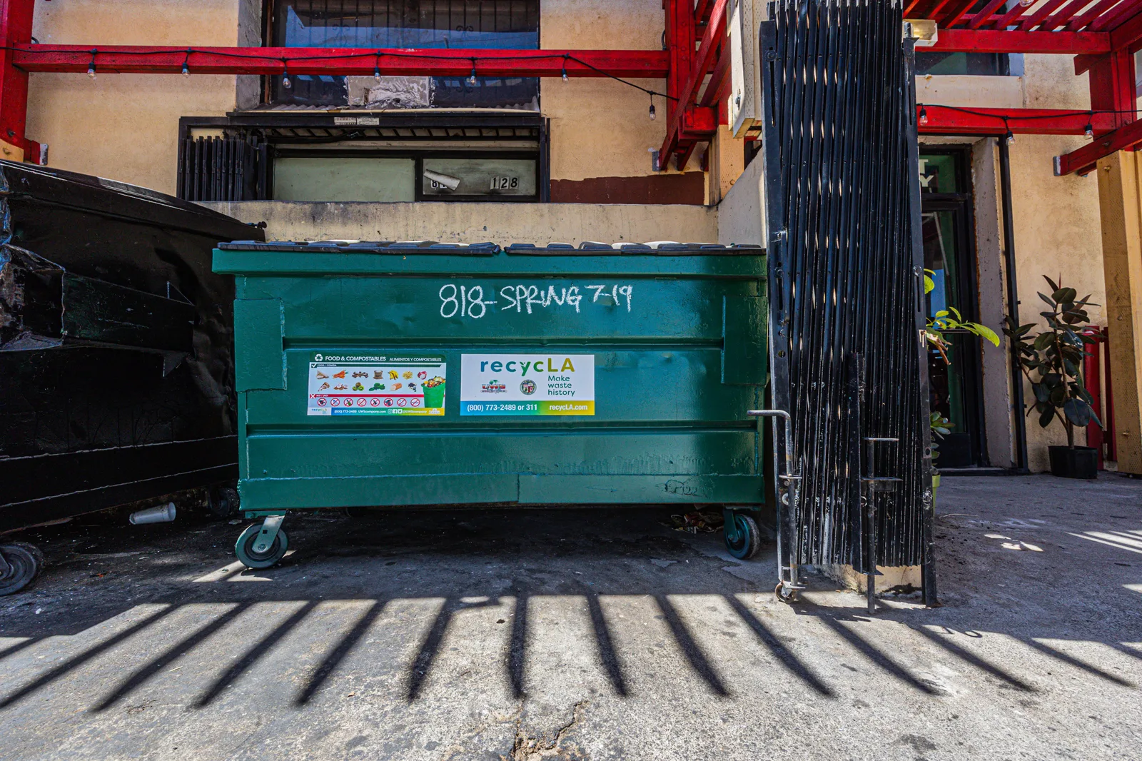 Front view of a green dumpster outside an urban building under daylight. Dumpster Rental Phone Scripts: How to Qualify Leads and Close Same-Day Rentals