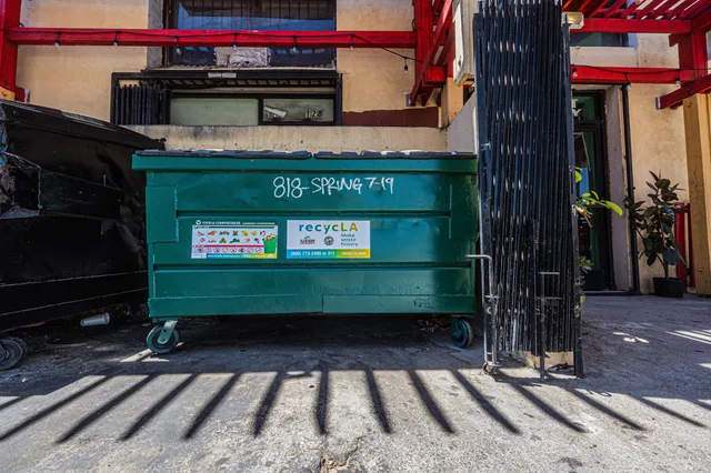 Front view of a green dumpster outside an urban building under daylight. Dumpster Rental Phone Scripts: How to Qualify Leads and Close Same-Day Rentals