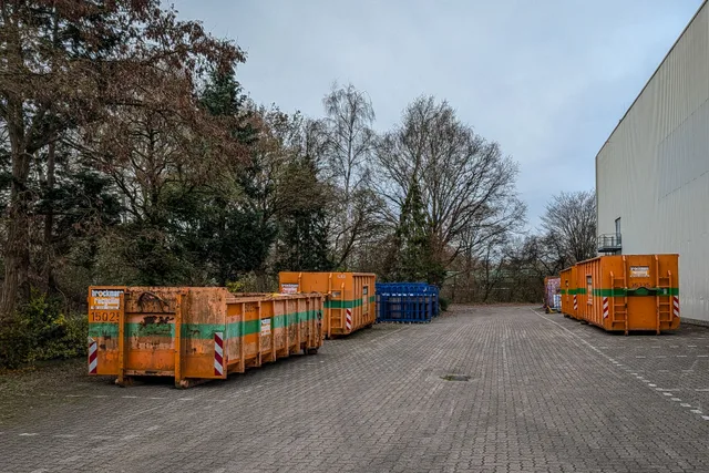 Outdoor view of industrial waste bins lined up beside a warehouse in winter. The margin math behind a dumpster rental business