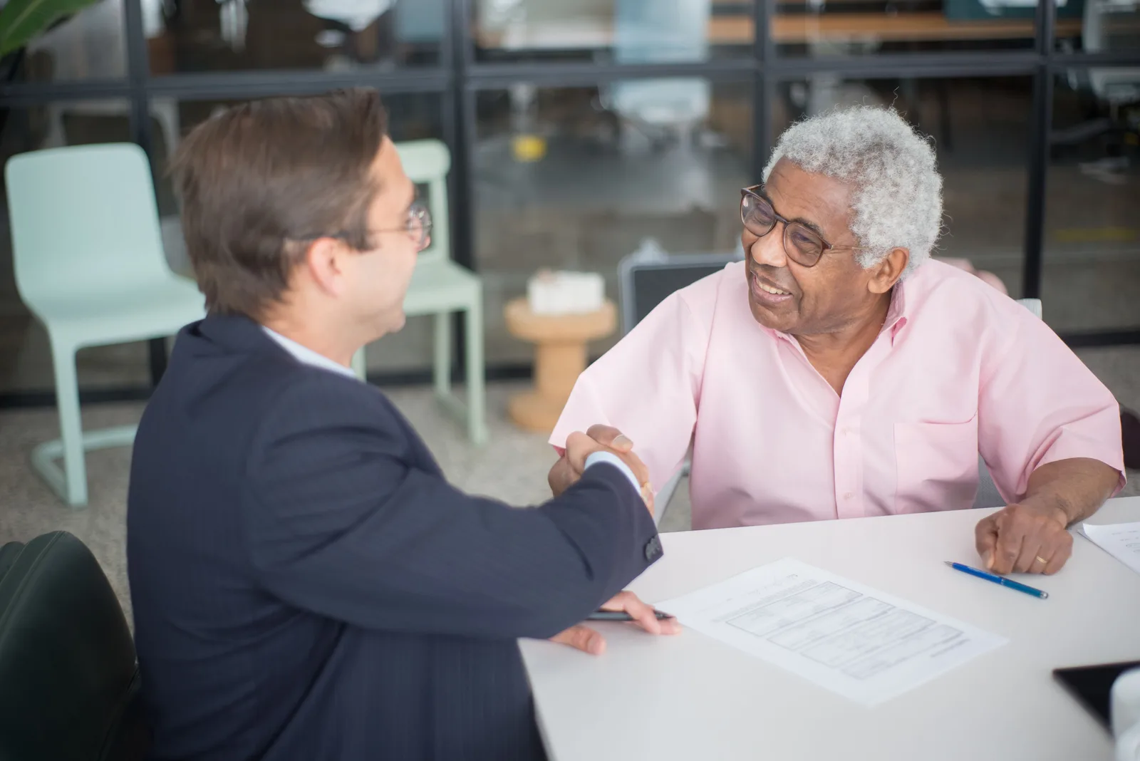 Two businessmen shaking hands in an office, sealing a deal. The referral engine inside a dumpster rental business
